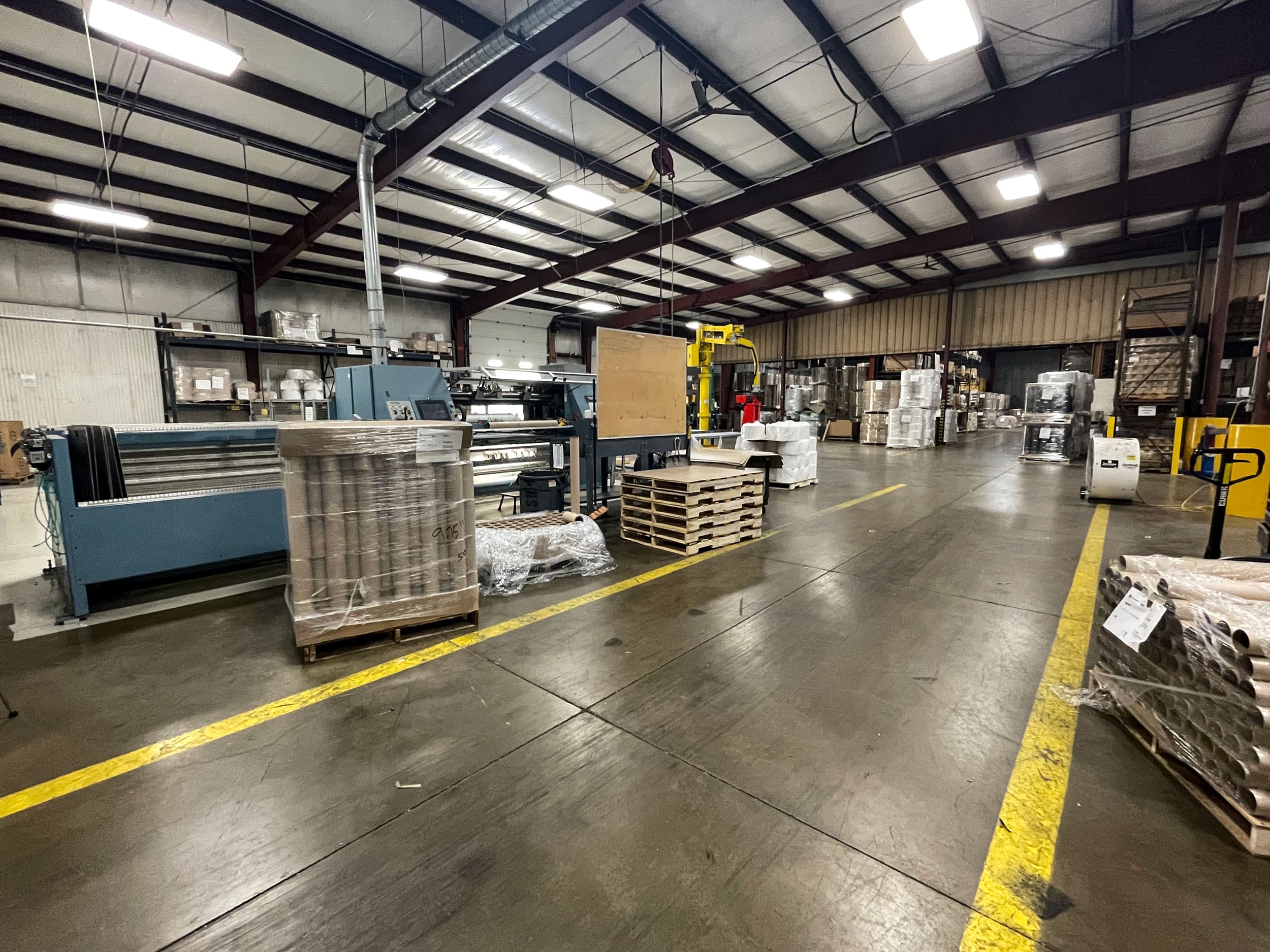 Wide view of the production floor at Paper Dimensions, with converting equipment and palletized material