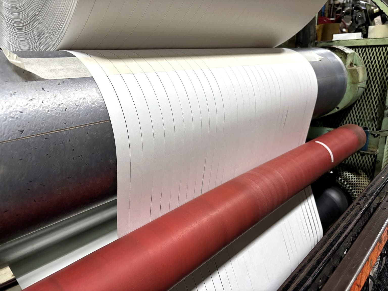 Paper slit into narrow ribbon widths at Paper Dimensions — the same slitting process used to convert Tag Stock to reinforcement-patch widths