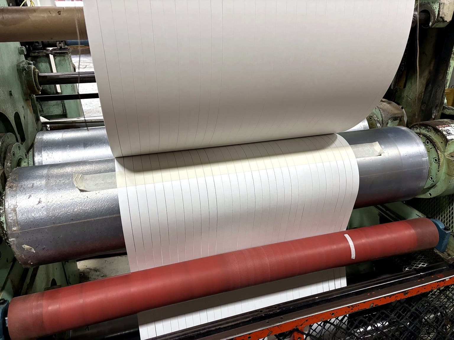 Paper moving through the slitting process on the production floor at Paper Dimensions in Beaver Dam, Wisconsin