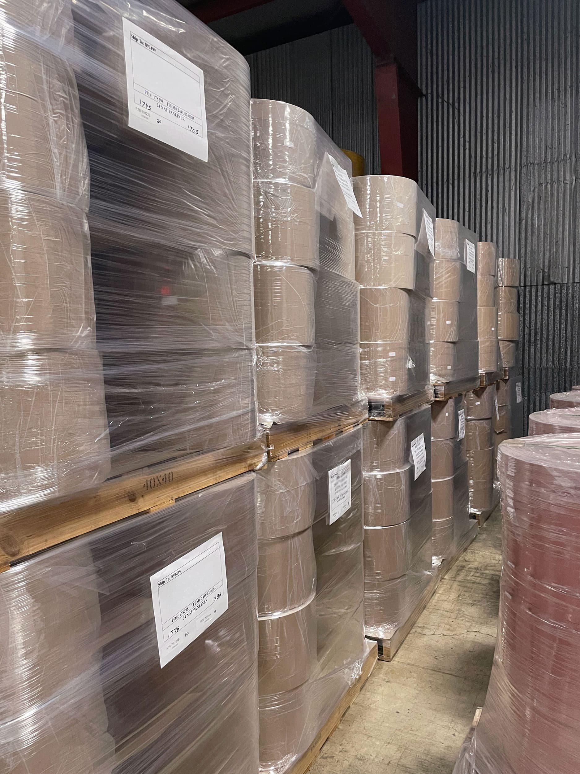 Stacked pallets of wrapped finished paper rolls in the Paper Dimensions warehouse