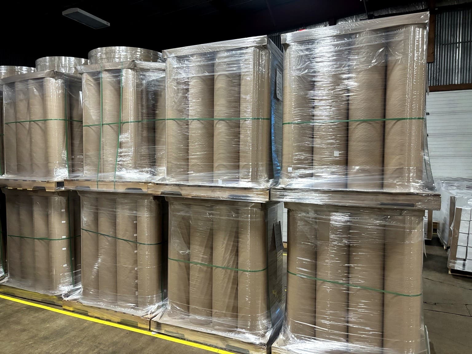 Uniformly rewound finished paper rolls stacked in the Paper Dimensions warehouse, showing consistent roll diameters