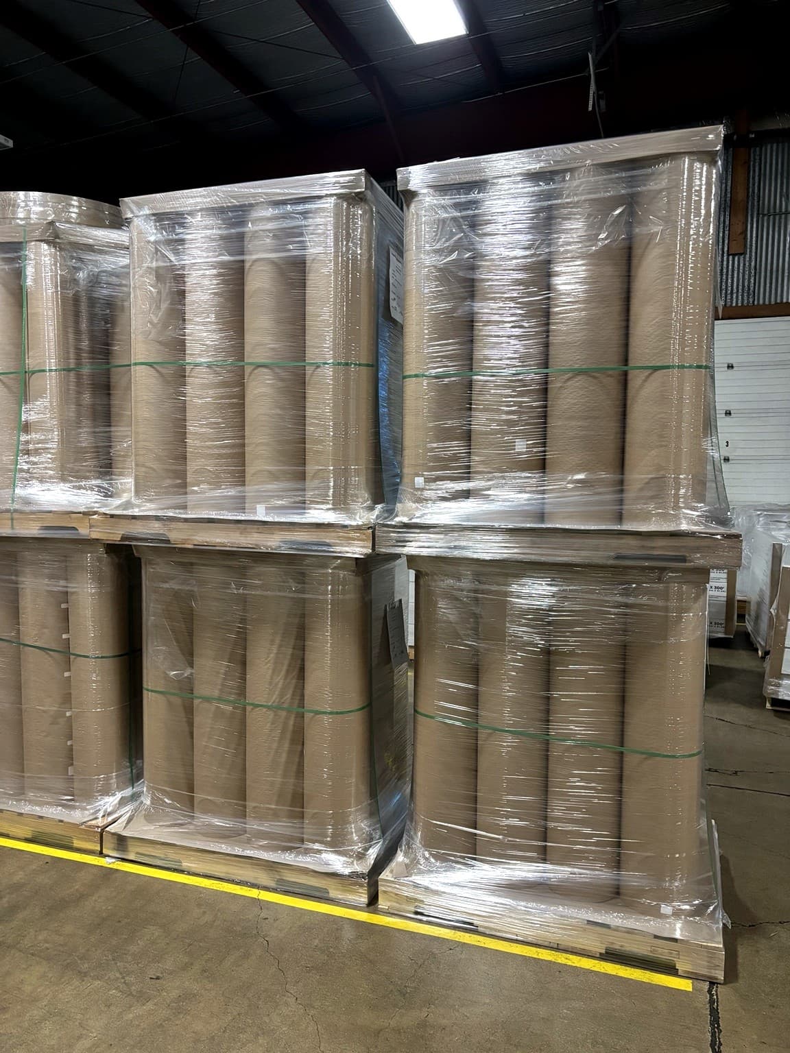 Individually wrapped rewound paper rolls staged in the Paper Dimensions warehouse, ready for customer-arranged freight